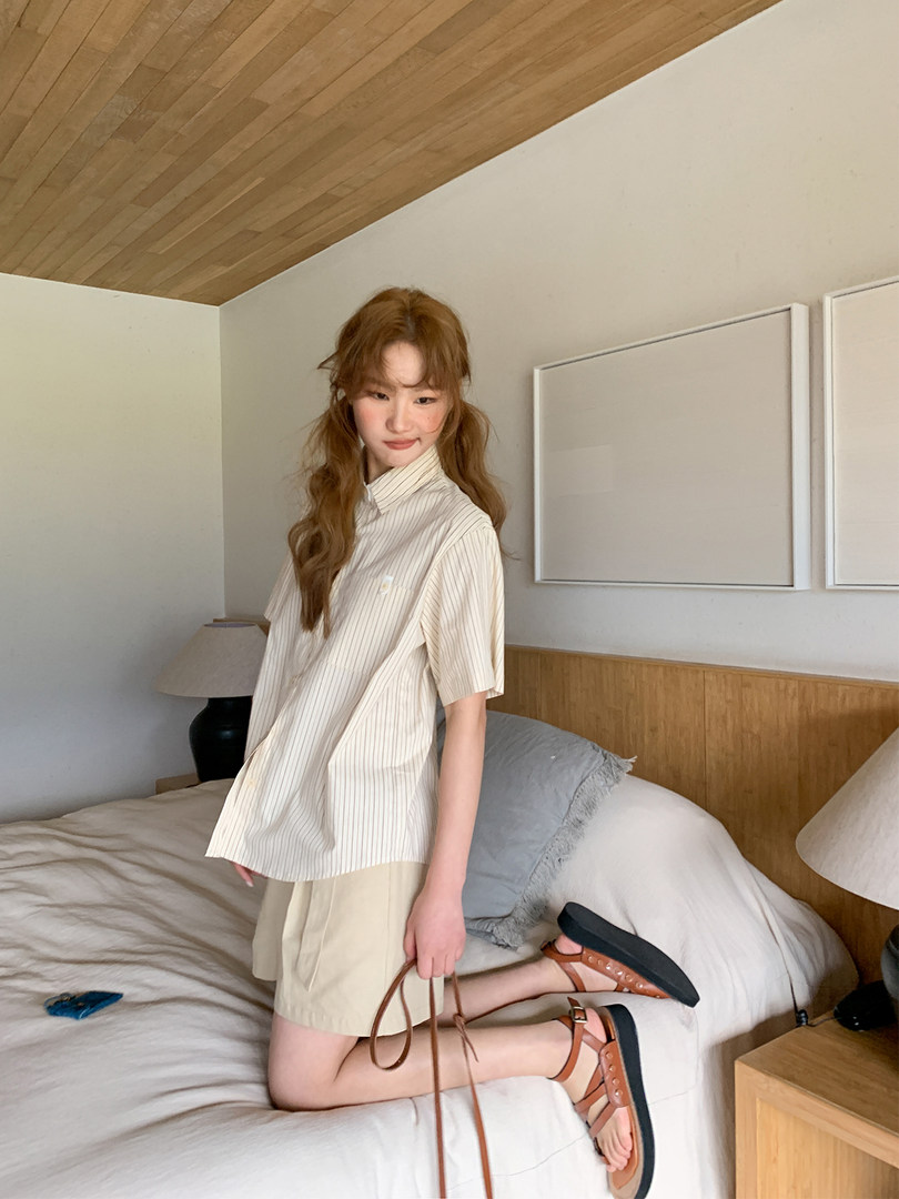 Model wearing a striped short-sleeve shirt, beige shorts, and brown sandals