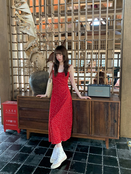 Woman wearing a red polka dot sleeveless midi dress with white sneakers