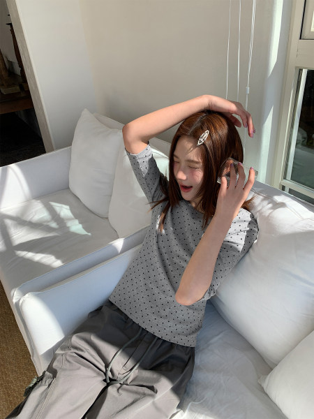 Gray polka dot short-sleeve top and loose pants worn by a model on a sofa