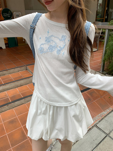 Model wearing a white long-sleeve top with blue suspenders and a flared skirt