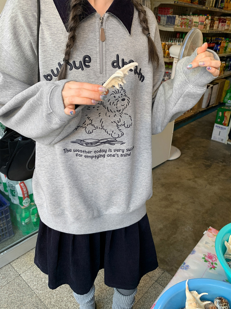 Model wearing a gray oversized graphic zip-collar sweatshirt with a dog print