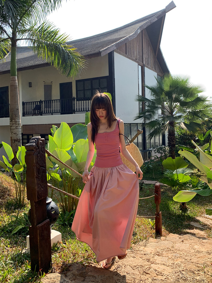 Woman wearing a pink maxi dress in a tropical resort setting