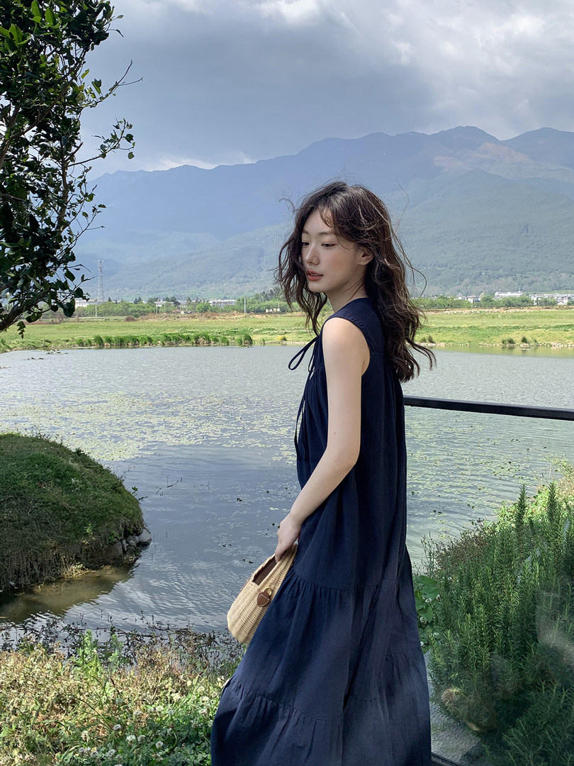 Woman wearing a navy sleeveless maxi dress outdoors by a lakeside