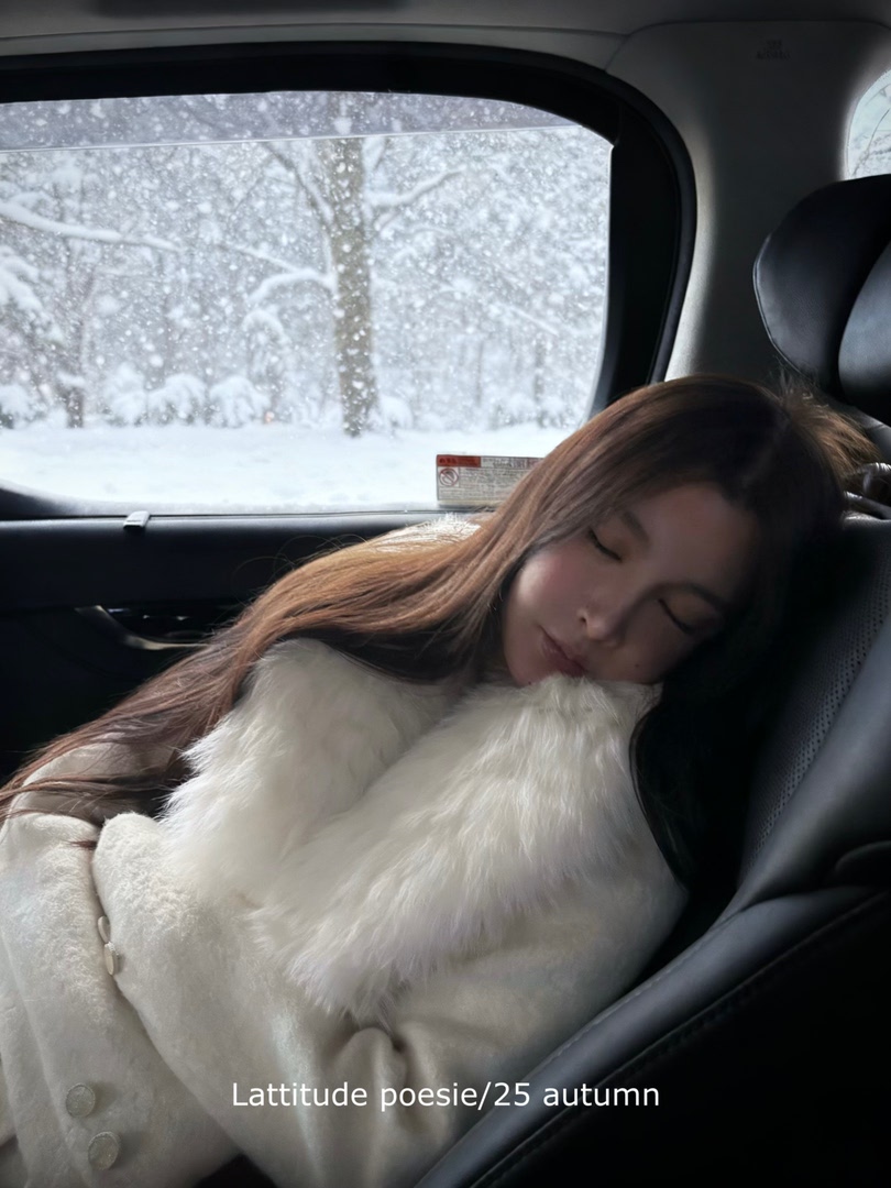 Woman wearing a white faux-fur winter coat in a snowy car scene