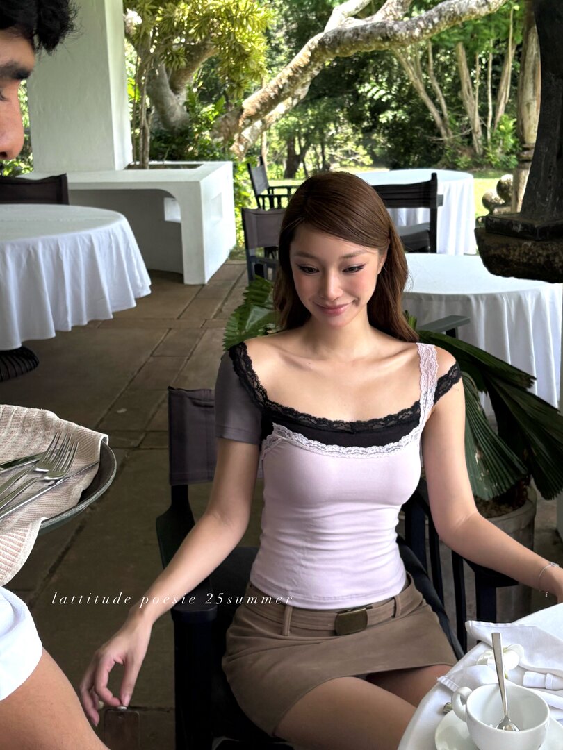 Woman wearing a light pink lace-trim camisole top with brown mini skirt at an outdoor dining setting