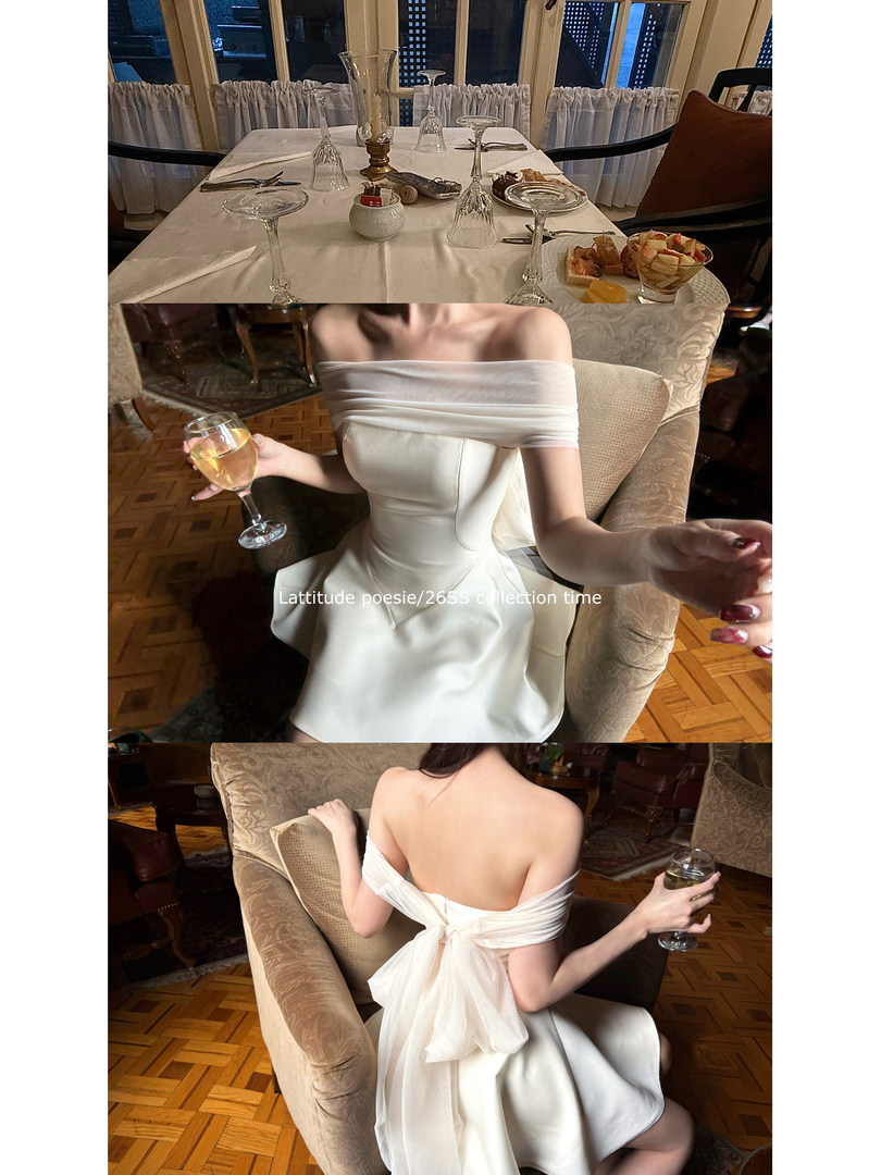 White off-shoulder formal dress worn by a model in a restaurant setting