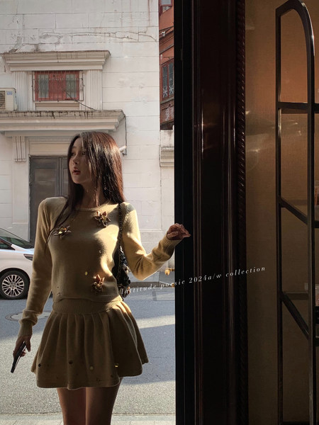 Woman wearing a tan knit sweater and matching skirt outdoors
