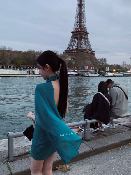 Woman wearing a teal backless dress by the Eiffel Tower