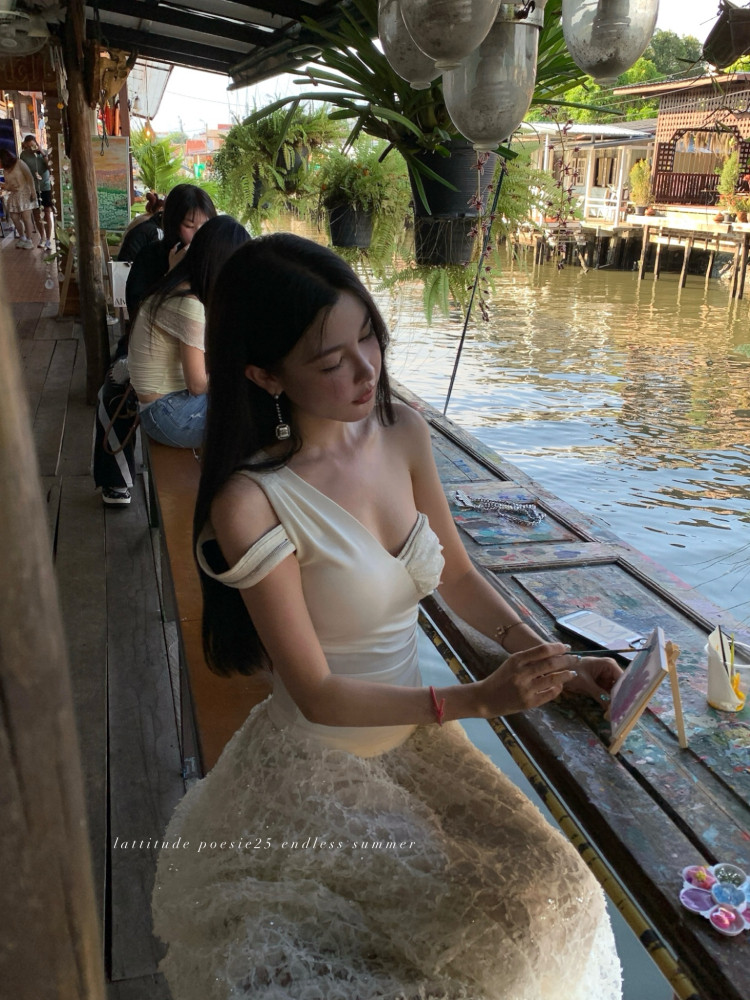 Woman wearing a white off-shoulder lace dress by the water