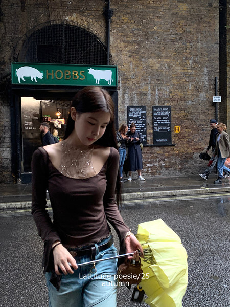 Woman wearing a brown fitted long-sleeve top and jeans on a city street