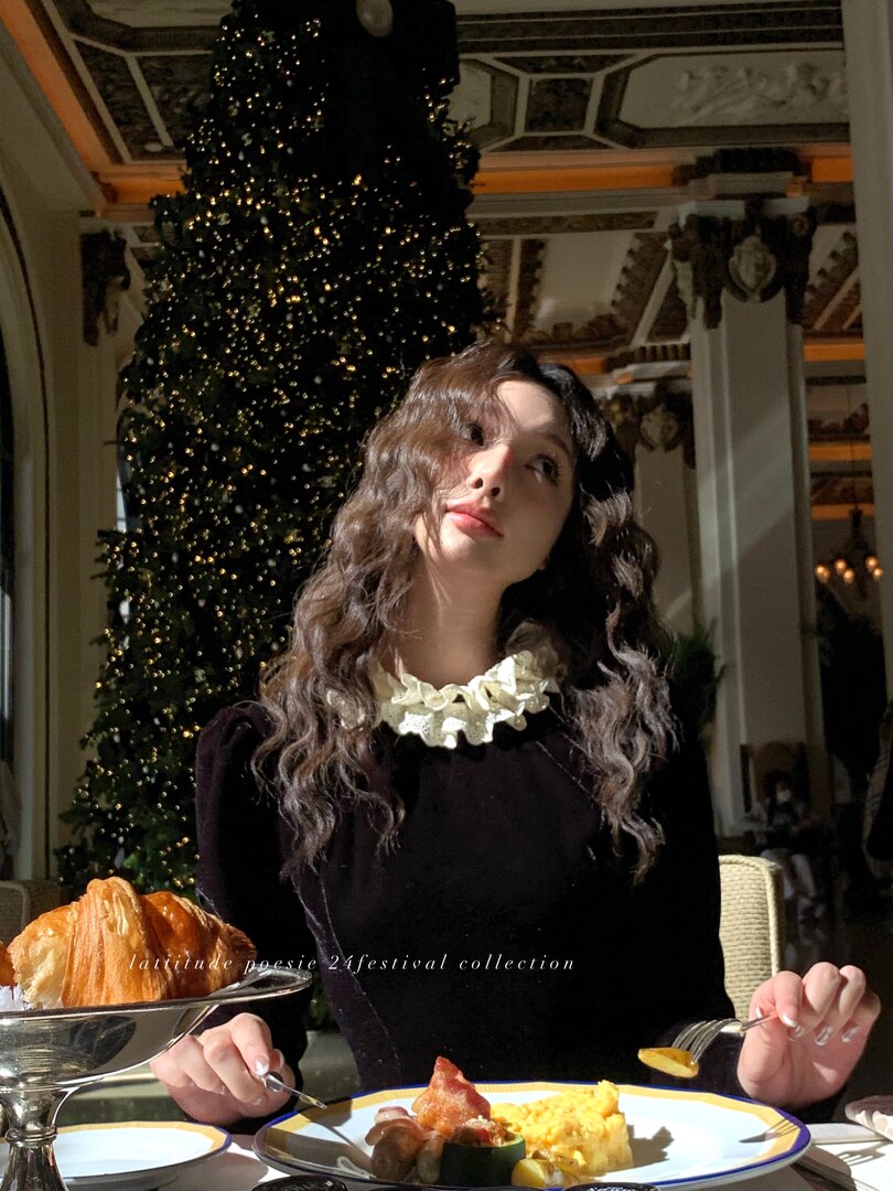 Woman wearing a black velvet dress with a ruffled white collar in a festive holiday setting