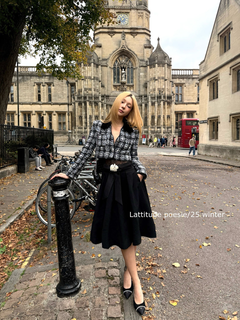 Woman wearing a black-and-white tweed jacket and black skirt outdoors