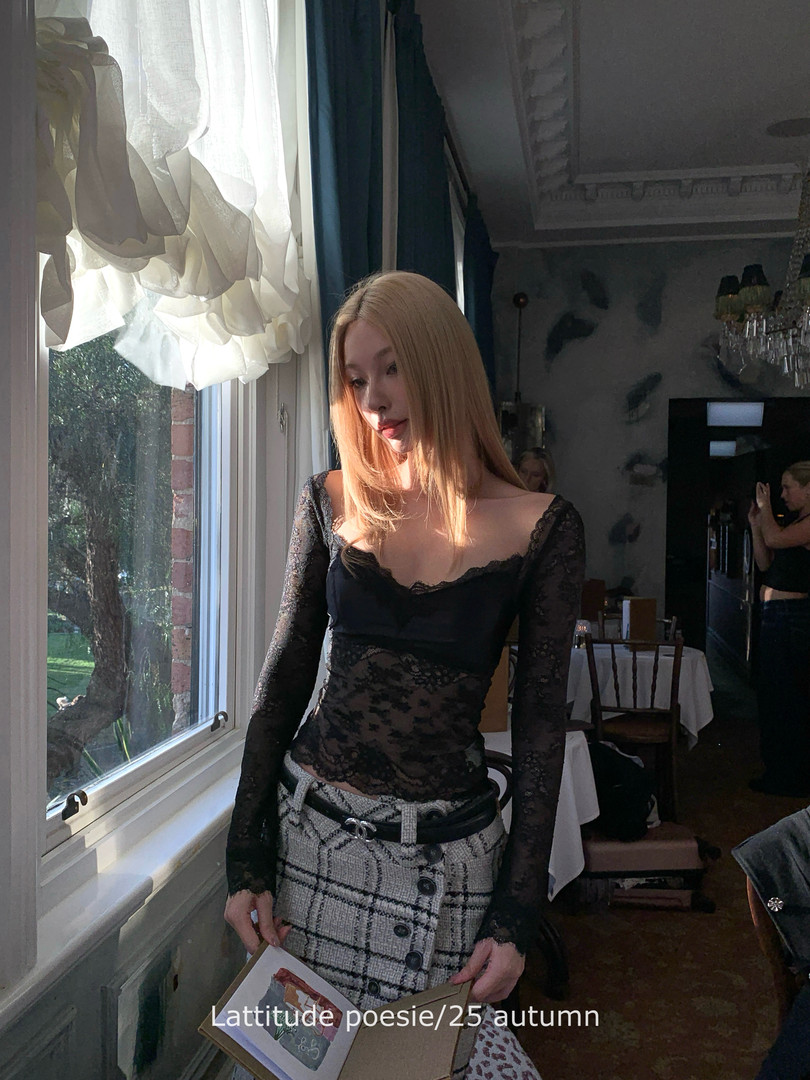 Woman wearing a black lace top and plaid skirt outfit indoors