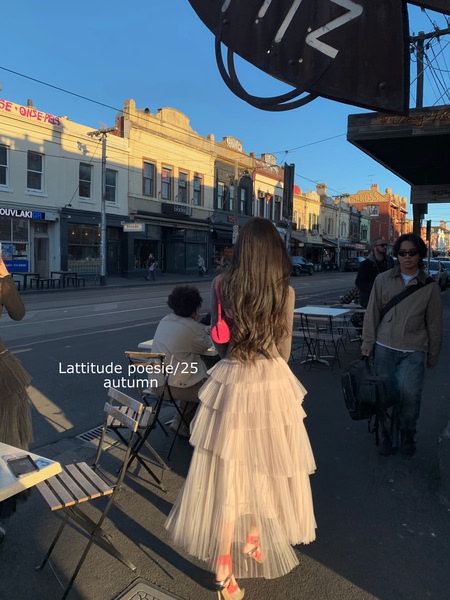 Woman wearing a cream pleated tulle dress on a city street