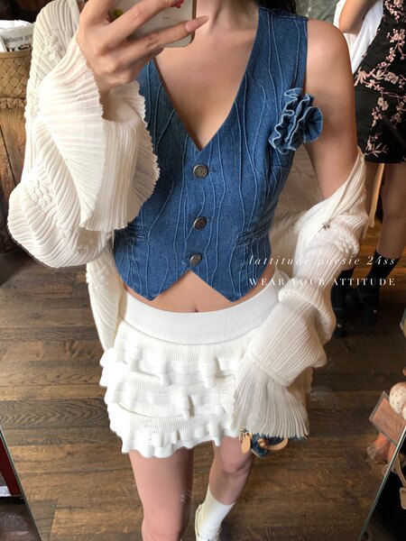 Model wearing a blue denim vest top with a white ruffled mini skirt and cardigan
