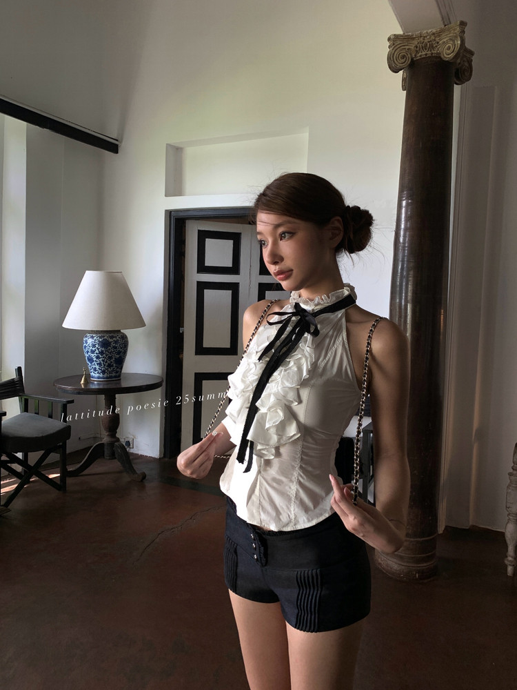 Woman wearing a white ruffled halter top with black shorts