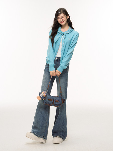 Model wearing a blue cardigan and wide-leg jeans with a denim shoulder bag