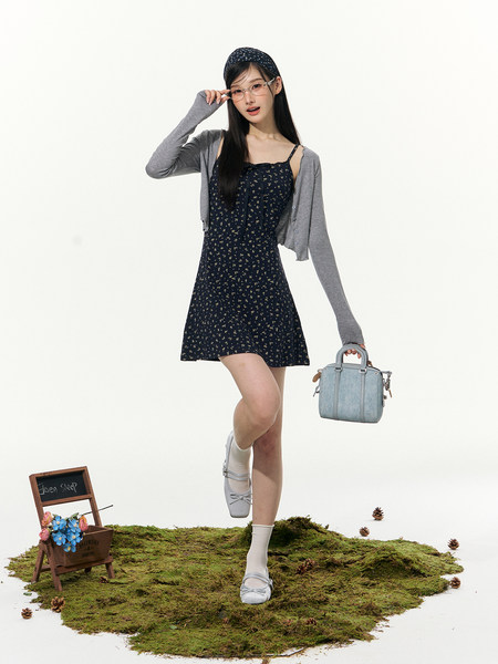 Model wearing a navy floral mini dress with a gray cardigan, headband, handbag, and flats.