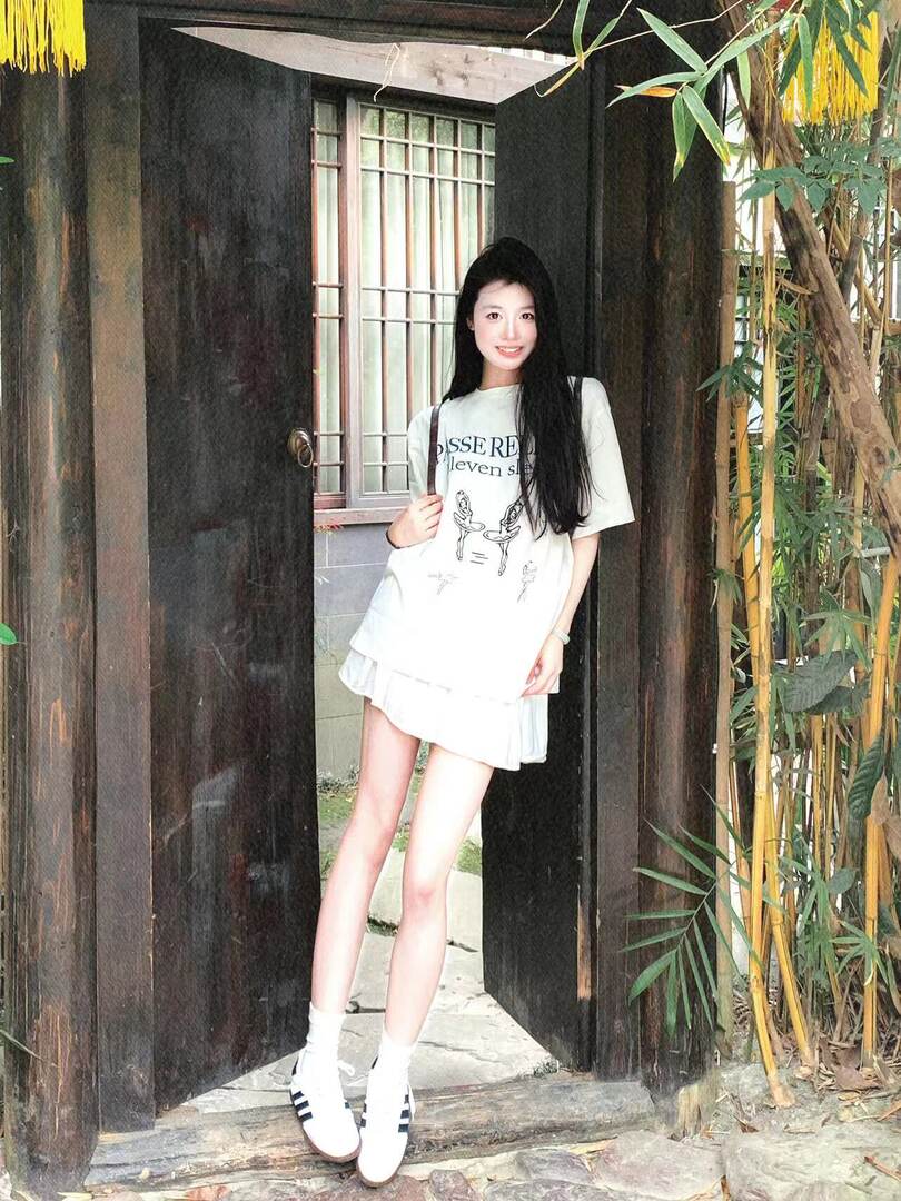 Woman modeling a white casual graphic T-shirt outfit with white sneakers outdoors