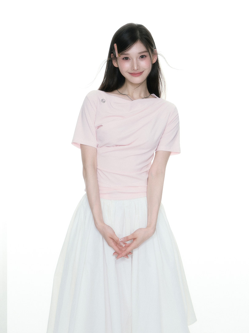 Model wearing a light pink short-sleeve top with a white flowy skirt on a white background
