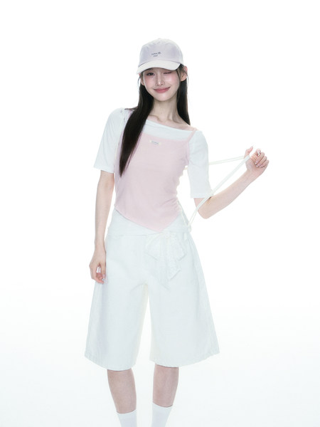 Model wearing a pastel pink and white casual outfit with a cap and shorts