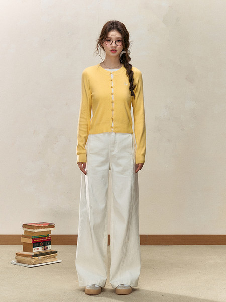 Model wearing a yellow button-front cardigan with white wide-leg pants