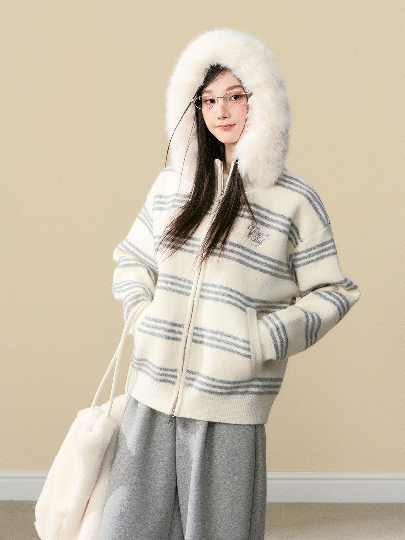 Model wearing a white striped zip-up hooded sweater with a fluffy fur hood