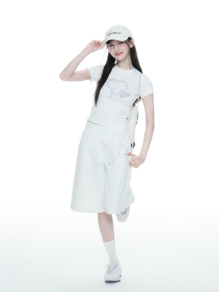 Model wearing a white casual outfit with cap, top, skirt, and sneakers