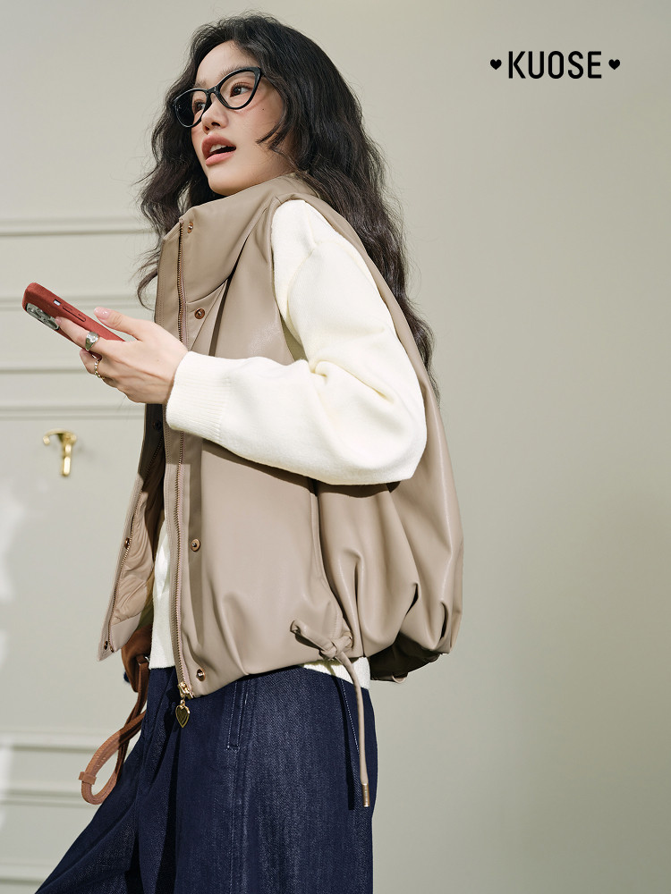 Model wearing a beige sleeveless jacket vest over a white sweater