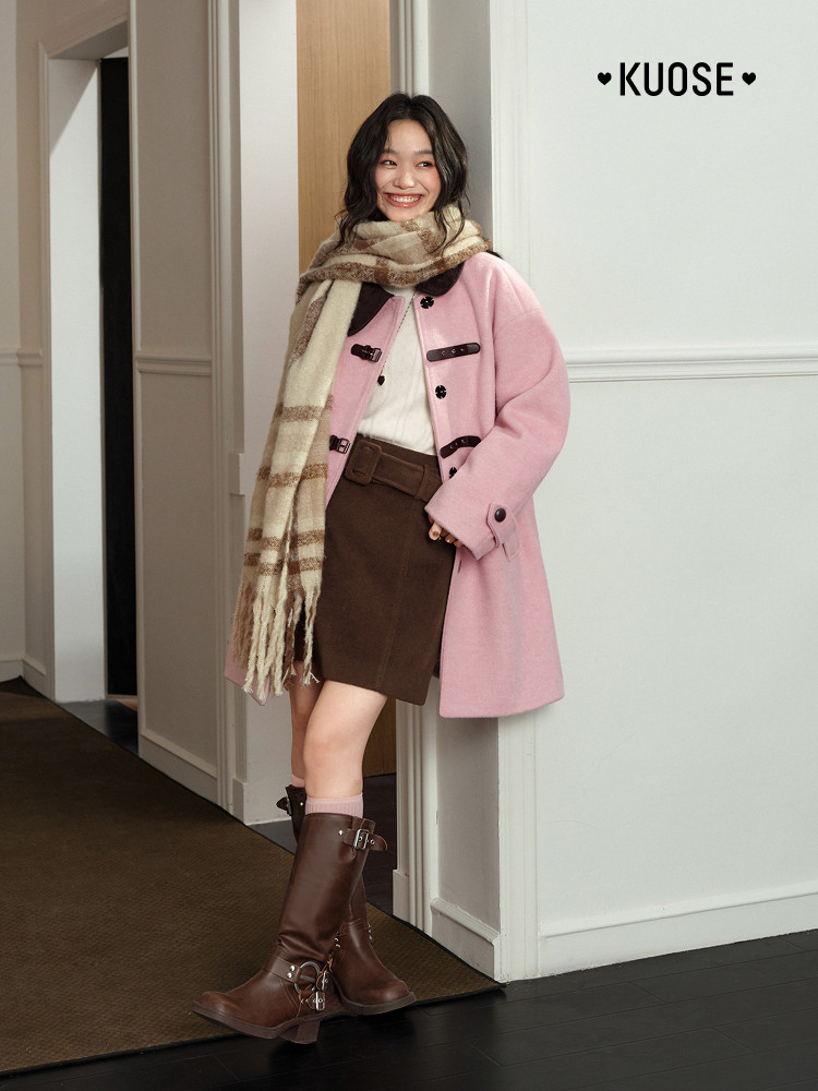 Model wearing a pink coat with plaid scarf and brown boots