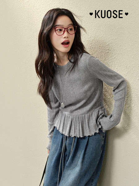 Woman wearing a gray ribbed long-sleeve peplum top with jeans