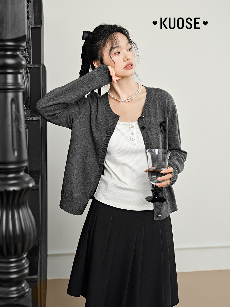 Model wearing a dark gray cardigan over a white top with a black skirt