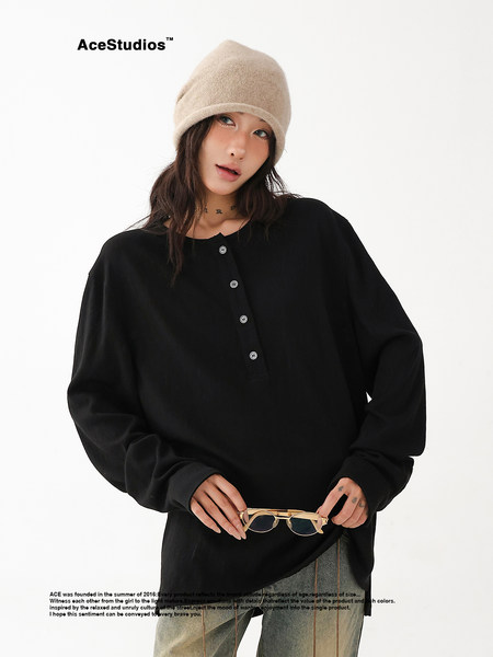 Model wearing a black oversized long-sleeve top with a beige beanie