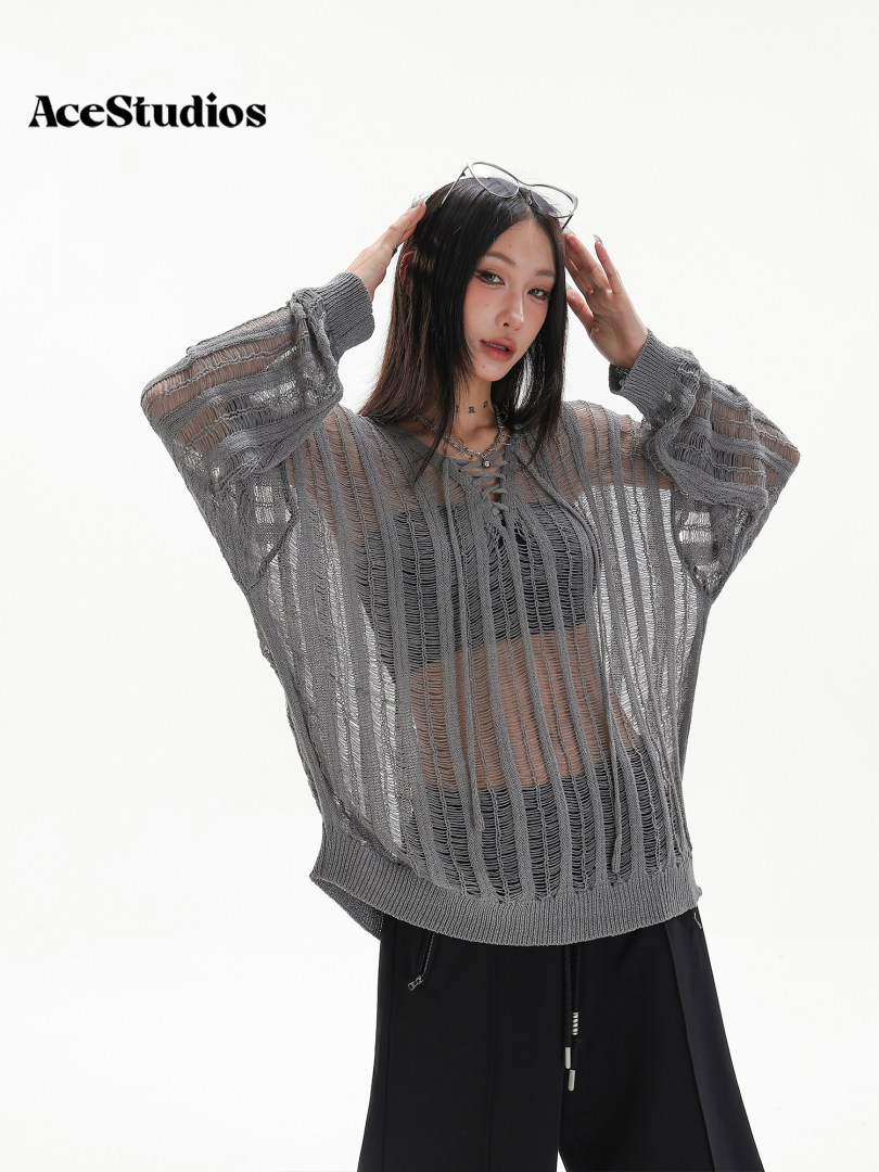 Model wearing a gray oversized sheer knit sweater with distressed texture