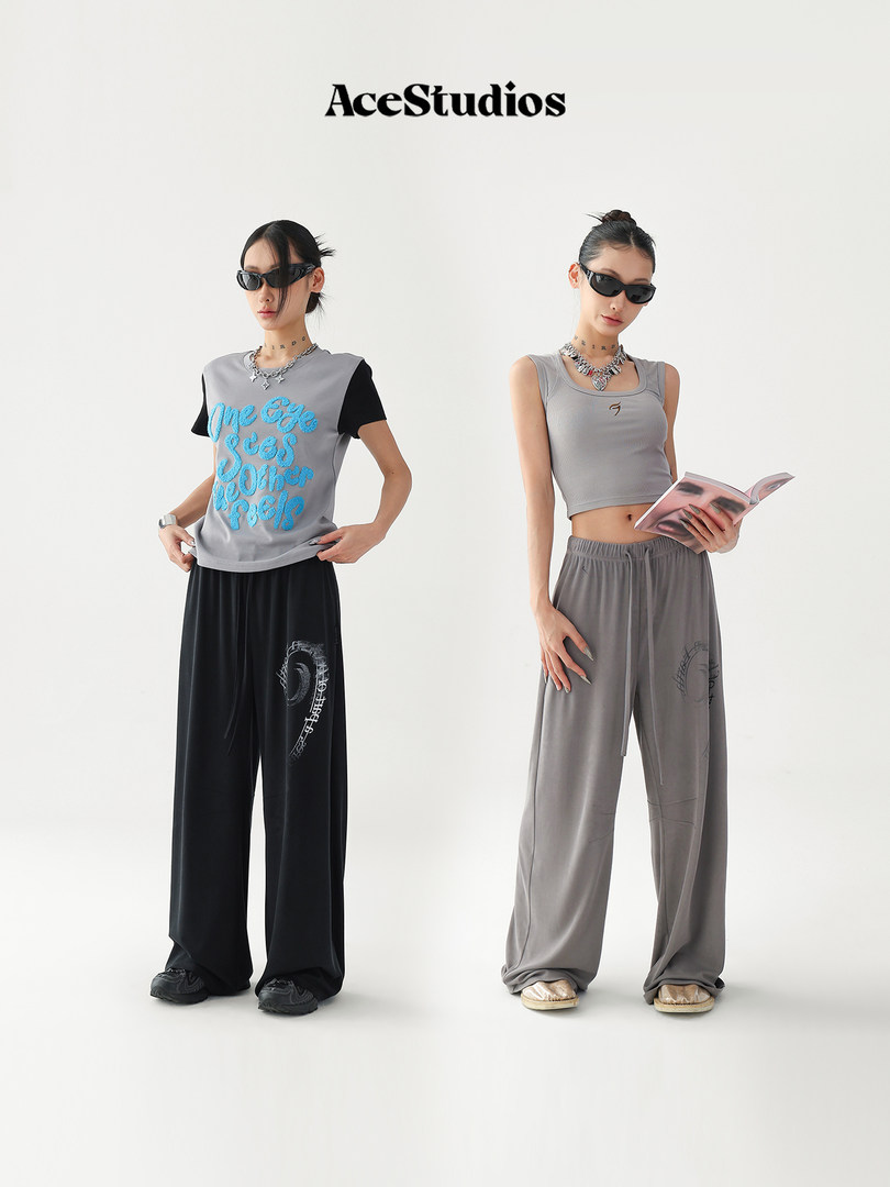 Two models wearing gray and black streetwear outfits with wide-leg pants