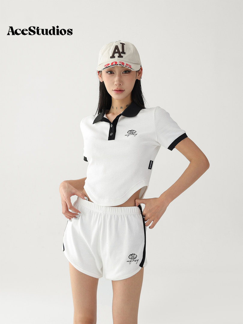 Model wearing a white and black polo top with matching shorts and cap