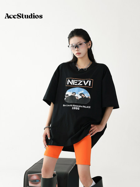 Model wearing an oversized black graphic T-shirt with orange shorts