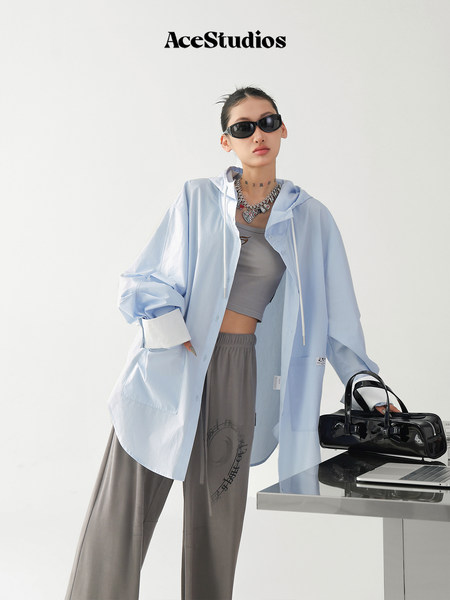 Model wearing a light blue oversized shirt with gray pants and a handbag