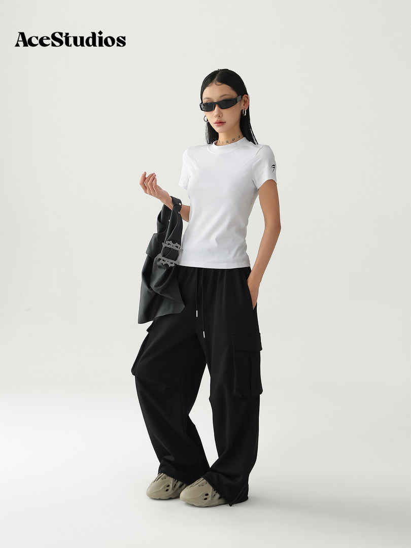 Model wearing a white fitted T-shirt with black wide-leg cargo pants and accessories