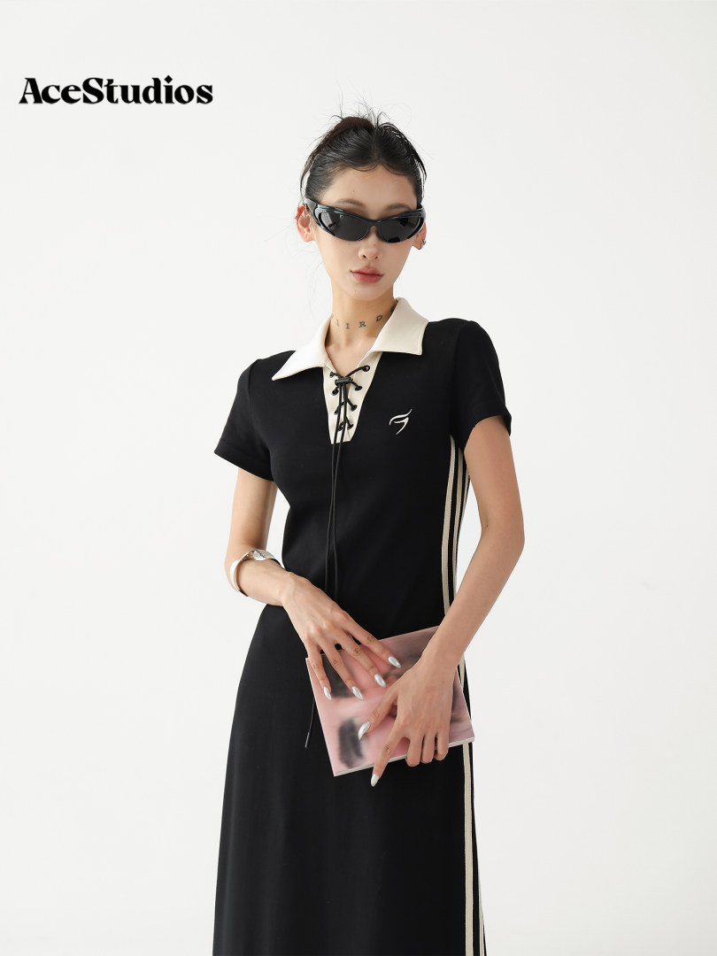 Model wearing a black short-sleeve dress with a white collar and lace-up front