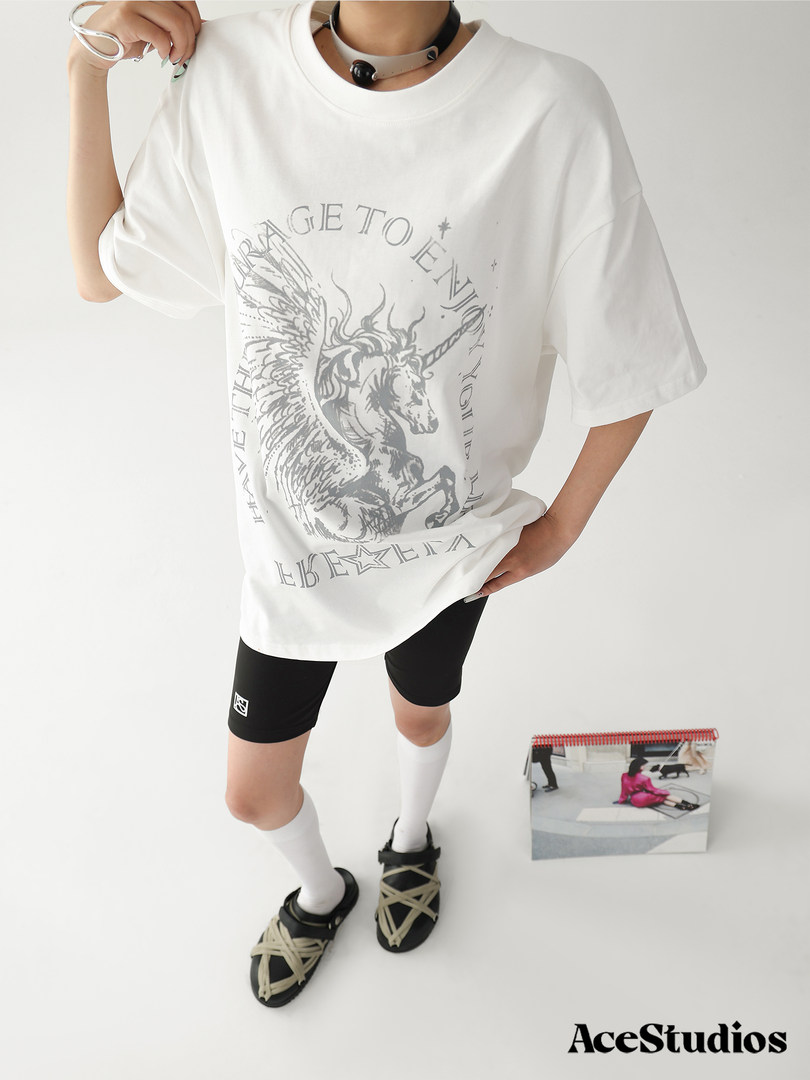 Model wearing an oversized white graphic T-shirt with a unicorn print