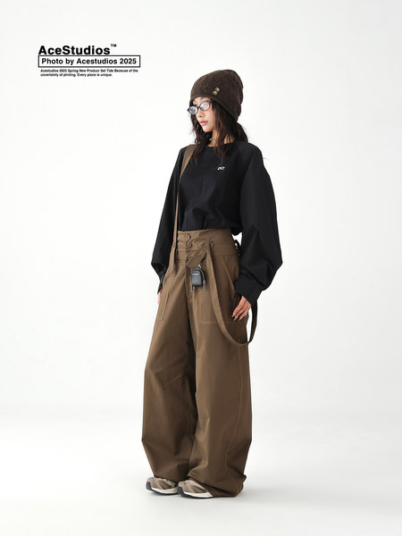 Fashion model wearing a black long-sleeve top and oversized brown wide-leg pants