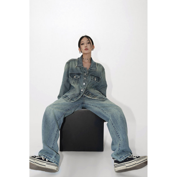 Model wearing a distressed denim jacket and wide-leg jeans with black sneakers