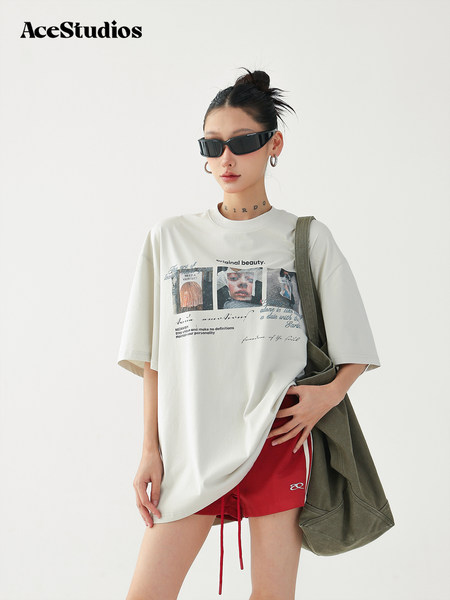 Model wearing an oversized graphic T-shirt with red shorts and a tote bag