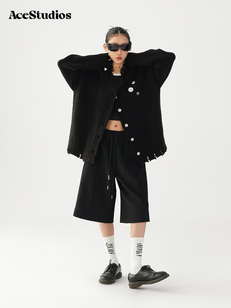 Model wearing a black oversized cardigan with cropped pants and loafers