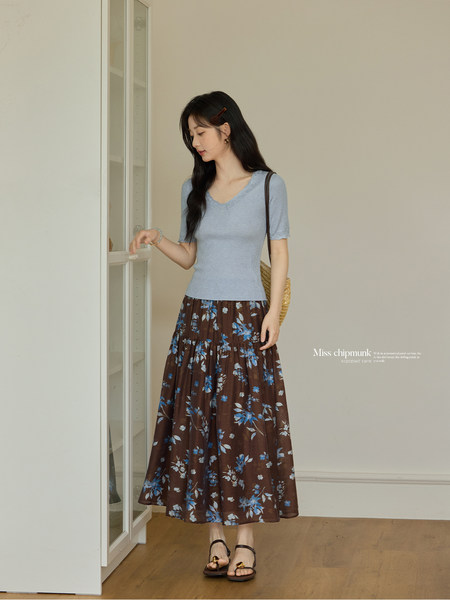 Woman wearing a light blue knit top with a brown floral maxi skirt