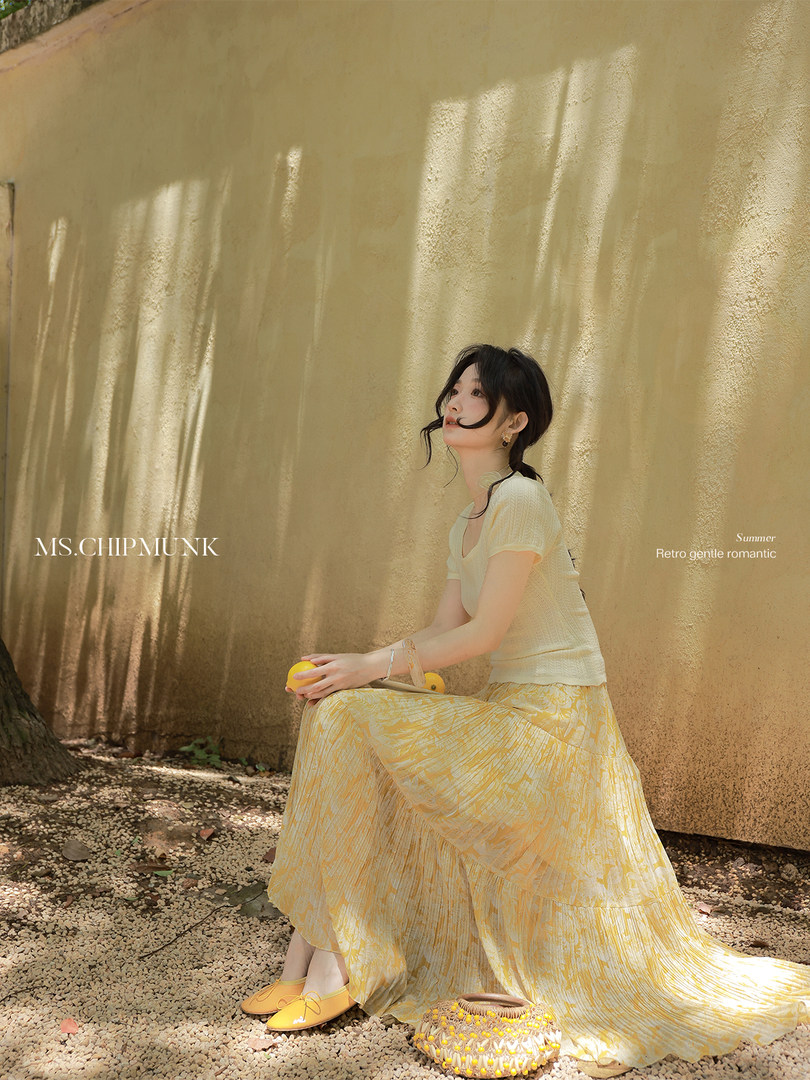 Model wearing a light yellow summer outfit with a cream top and flowing skirt outdoors