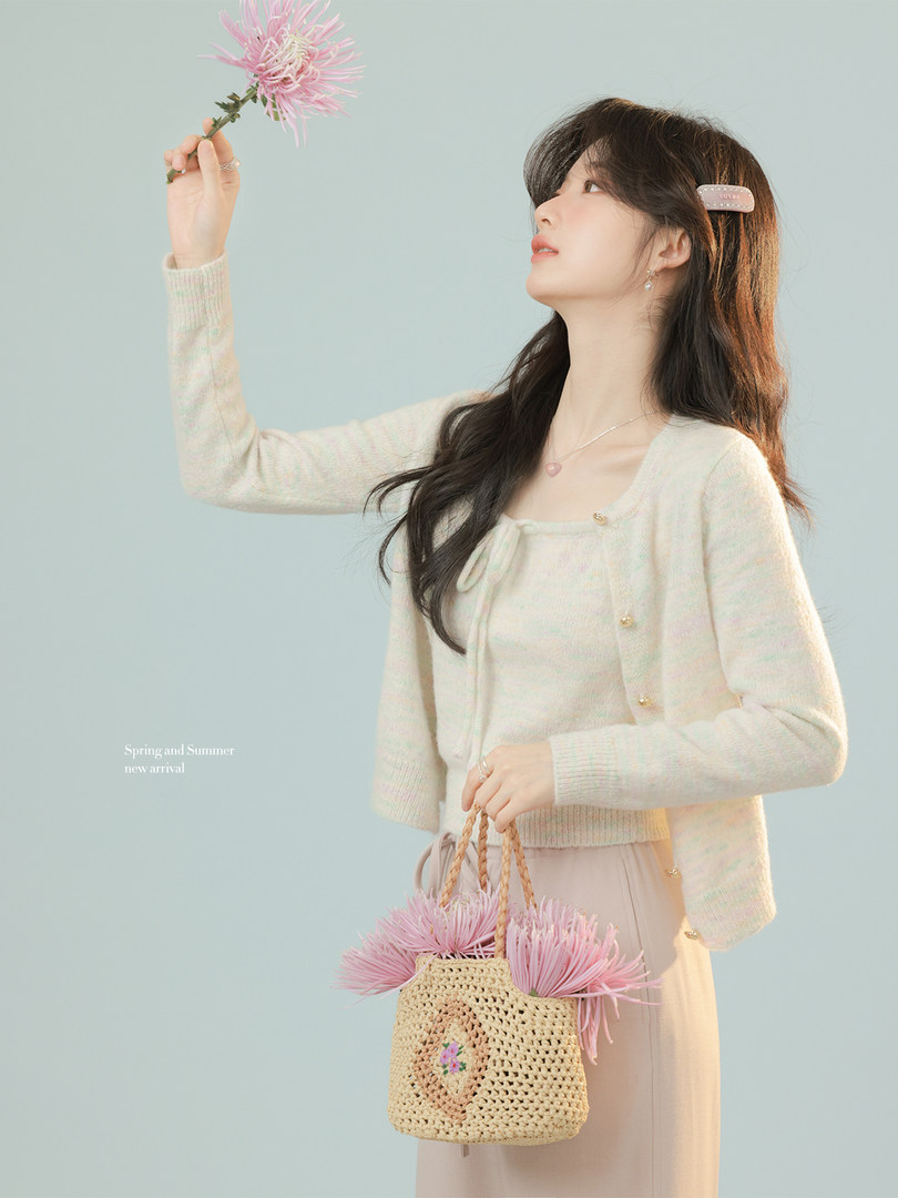 Woman wearing a cream cardigan and skirt with a woven straw handbag