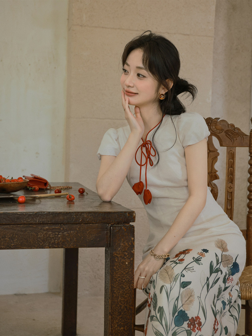 Woman wearing a white floral dress with red tie detail