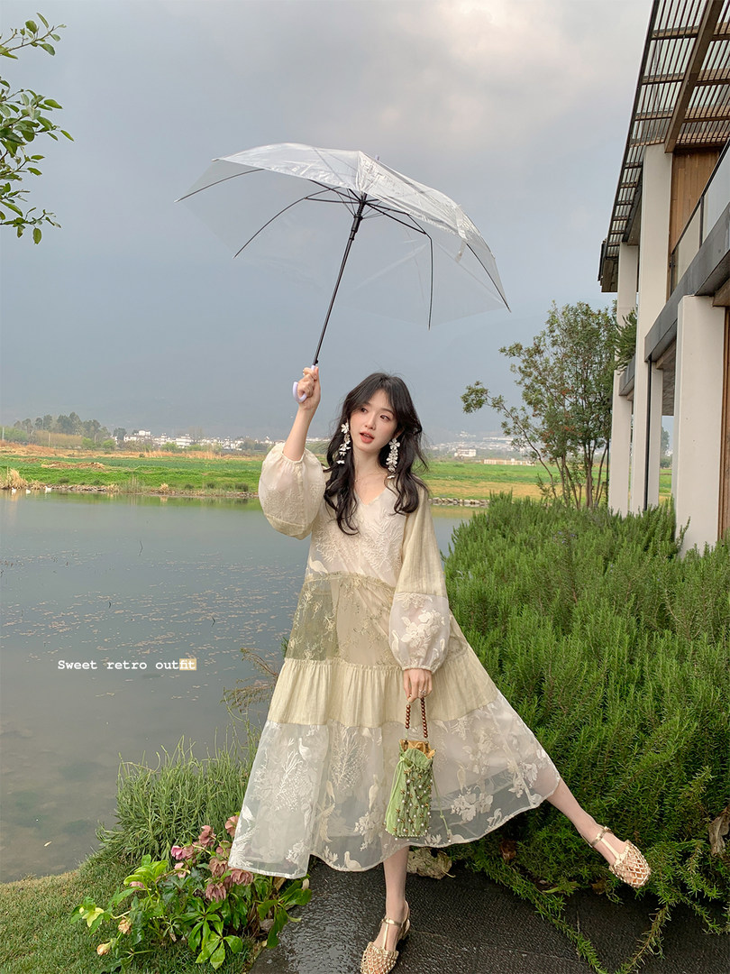 Woman wearing a light floral retro dress outdoors under an umbrella